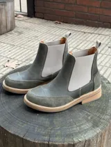 Botas Chelsea color verde oliva, combinadas en cuero liso y gamuza, con elásticos laterales color gris claro y tirador trasero.