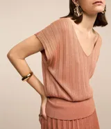 Blusa de manga corta color salmón, confeccionada en viscosa con escote en pico e hilos metalizados con textura efecto plisado. Tiene un diseño más ajustado en la cintura.