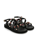 Sandalias negras con plataforma, tiras con apliques de tachas doradas y piedras rojas.