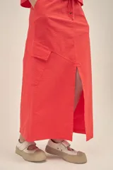 Falda larga color coral, estilo cargo, con cintura regulable con cordón, tajo frontal y bolsillos laterales con solapa.