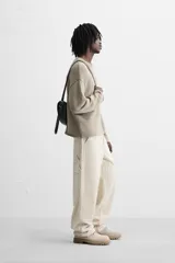 Pantalón de pana color crema, corte relaxed fit, con bolsillos frontales, bolsillos de parche en la parte trasera, bolsillos laterales en las piernas, trabilla multifunción y cierre con cremallera y botón.