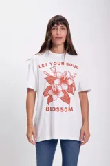 Remera blanca de corte oversize con estampado de flores color naranja y texto.