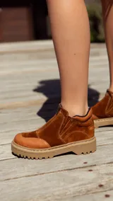 Bota corta color marrón óxido de cuero gamuzado, con plataforma de goma color beige y cierre frontal con cremallera.