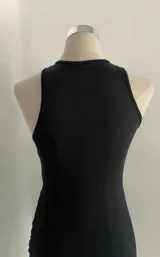Minivestido negro ajustado al cuerpo, con escote halter con abertura en forma de gota y falda drapeada.
