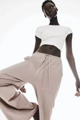 Pantalón largo color topo de punto de algodón, con cintura elástica ajustable con cordón fino. Tiene bolsillos laterales discretos y corte recto.