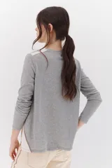 Remera color blanco con detalles en gris, de manga larga y corte suelto.