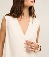 Chaleco largo color crema, con botones delanteros y lazo en la espalda.