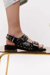 Sandalias bajas color crema con apliques de tachas metálicas y hebillas plateadas.