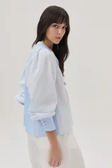 Blusa celeste a rayas verticales blancas, con cuello mao con lazos, mangas abullonadas y corte imperio.