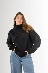 Sweater negro tejido en punto arroz, con cuello alto, mangas largas y silueta holgada.