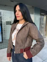 Chaqueta bomber marrón con capucha, cierre frontal con cremallera, puños y bajo en color borgoña.