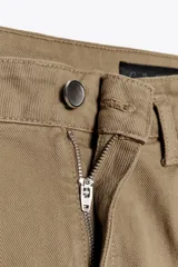 Pantalón cropped color beige de tiro alto y corte recto, confeccionado en algodón. Cuenta con bolsillos delanteros y traseros, trabillas en la cintura y cierre frontal con cremallera y botón.