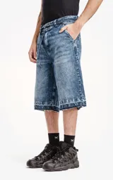 Bermuda de denim larga con calce oversize, desgaste y ruedo desflecado.