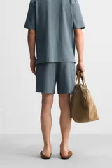Bermuda azul de tejido con mezcla de algodón, corte relaxed fit, cintura elástica ajustable con cordón, bolsillos delanteros y detalle de bolsillo trasero de vivo.