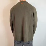 Sweater verde oliva de tejido grueso con cuello alto.