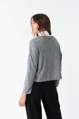 Cardigan tejido color beige con escote en V, cierre con botones, bolsillos delanteros y logo en grifa de cuero.