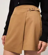 Short pollera de estilo sastre, color camel/marrón claro, con diseño de traspaso frontal asegurado por una hebilla.