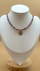 Collar de cinco hilos de cuentas facetadas de jade de Malasia color borgoña, con cuentas doradas y dijes colgantes dorados con incrustaciones de strass: estrella, espiral, mano de Fátima, luna creciente y esqueleto de pez.