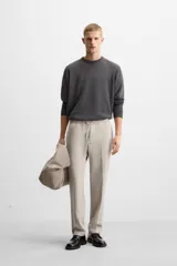 Pantalón color arena de corte recto, confeccionado en tejido elástico. Cuenta con cintura elástica ajustable con cordón, bolsillos laterales y bolsillos de vivo en la parte trasera.