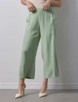 Pantalón de lino color crudo, de corte ancho y tiro alto, con bolsillos laterales y cintura elástica.