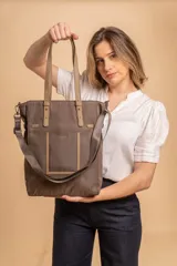 Cartera tipo tote bag color negro, con doble asa de mano y correa bandolera ajustable. Presenta un bolsillo rectangular en el frente.