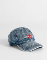 Gorra de denim celeste con efecto gastado, con bordado de corazón rojo y frase "Let's Grow Some" en blanco.