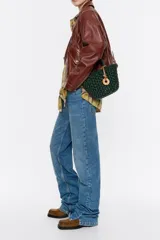 Bolso tipo tote de mimbre color marrón oscuro, con doble asa corta y correa de cuero marrón. Incluye dije circular dorado con letras grabadas.