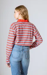 Camiseta de manga larga con cuello polo, rayas horizontales marrones y celestes, y cuello y tapeta de botones en color celeste liso.