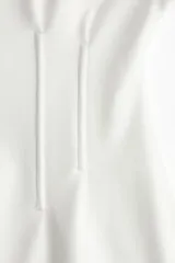 Remera larga color blanco de punto pesado de algodón, con escote barco, hombros caídos, mangas al codo y cintura entallada con pinzas acolchadas.