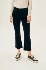 Pantalón de pana negro, tiro medio, corte ajustado hasta la rodilla y acampanado en la parte inferior, con terminación desflecada.