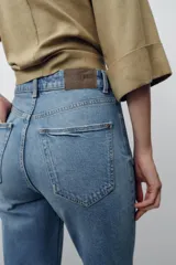 Jeans de tiro alto color celeste, corte mom fit, con cinco bolsillos y cierre frontal con cremallera y botón.