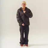 Campera puffer negra con capucha, corte holgado y bolsillos grandes. Presenta dos tonos de negro y texturas diferentes (satinado y mate).