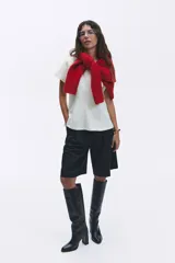 Remera blanca entallada de punto pesado interlock, con cuello redondo, mangas cortas, pinzas moldeadoras en la cintura y bajo acampanado.
