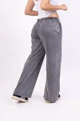 Pantalón deportivo gris con efecto lavado, corte ancho, cintura elástica y logo bordado en negro.