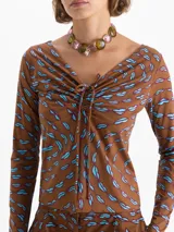 Top de punto color rojo con estampado de labios en azul y fucsia. Presenta escote en V profundo con jareta ajustable para anudar, mangas largas y calce al cuerpo.