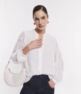 Camisa blanca de chiffon con mangas largas abullonadas, cuello mao, abotonado frontal y textura bordada con felpas.
