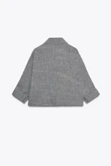 Chaqueta jaspeada color beige, con cuello solapa, manga tres cuartos con trabilla y botón, bolsillos delanteros de plastrón con solapa, bajo ajustable con cordones interiores y cierre frontal con botones a presión.