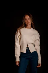 Buzo gris de punto con cuello redondo, mangas largas abullonadas y cierre frontal asimétrico.