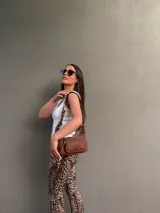 Cartera bandolera de cuero color marrón, con correa ajustable y bolsillo externo con cierre.