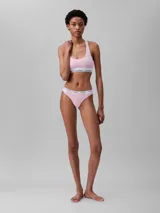 Conjunto Calvin Klein de ropa interior deportiva, compuesto por un corpiño con espalda racerback y una colaless, ambos en color rosado con elástico blanco con el logo de la marca.