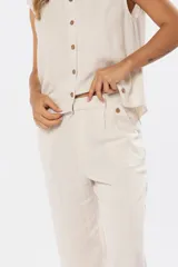 Pantalón de vestir color beige claro, confeccionado en tejido de lino y viscosa, con cintura parcialmente elastizada y pinzas frontales.