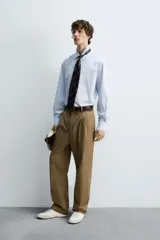 Camisa celeste de algodón con estructura twill, corte regular, cuello solapa, manga larga con puños abotonados y cierre frontal con botones.