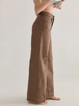 Pantalón gris de tiro medio alto, corte ancho, con bolsillos delanteros y traseros, detalles de atraques y triples costuras en color amarillo.