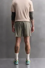 Shorts de entrenamiento color verde oliva, confeccionado en tejido técnico ligero y elástico con perforaciones. Tiene forro interior, cintura elástica ajustable con cordón, bolsillos laterales, bolsillo trasero con cierre de cremallera, bajo con aberturas laterales y logo estampado en la pierna.