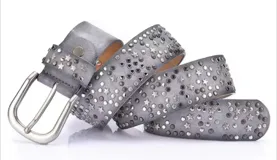 Cinto negro con tachas plateadas en forma de estrellas y círculos, con hebilla metálica plateada.