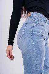 Jeans mom fit celeste claro con roturas en las rodillas.