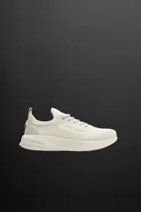 Zapatilla deportiva color crudo para uso diario y carreras ligeras. Parte superior de tejido de punto transpirable con puntera y talón recubiertos de material Shield Protect Max. Ajuste con cordones, tirador trasero y plantilla OrthoLite® extraíble. Entresuela con tecnología Spume Foam V3 y suela de goma.