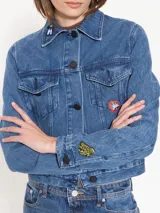 Campera de jean azul de calce estándar con bordados y parches de figuras emblemáticas del artista Edgardo Giménez.