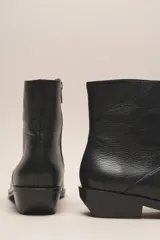 Bota corta de cuero vacuno color negro, con punta fina y taco bajo.