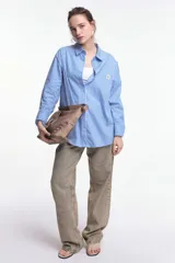 Camisa a rayas verticales rojas y blancas, de corte recto, con cuello clásico, manga larga y bolsillo en el pecho.